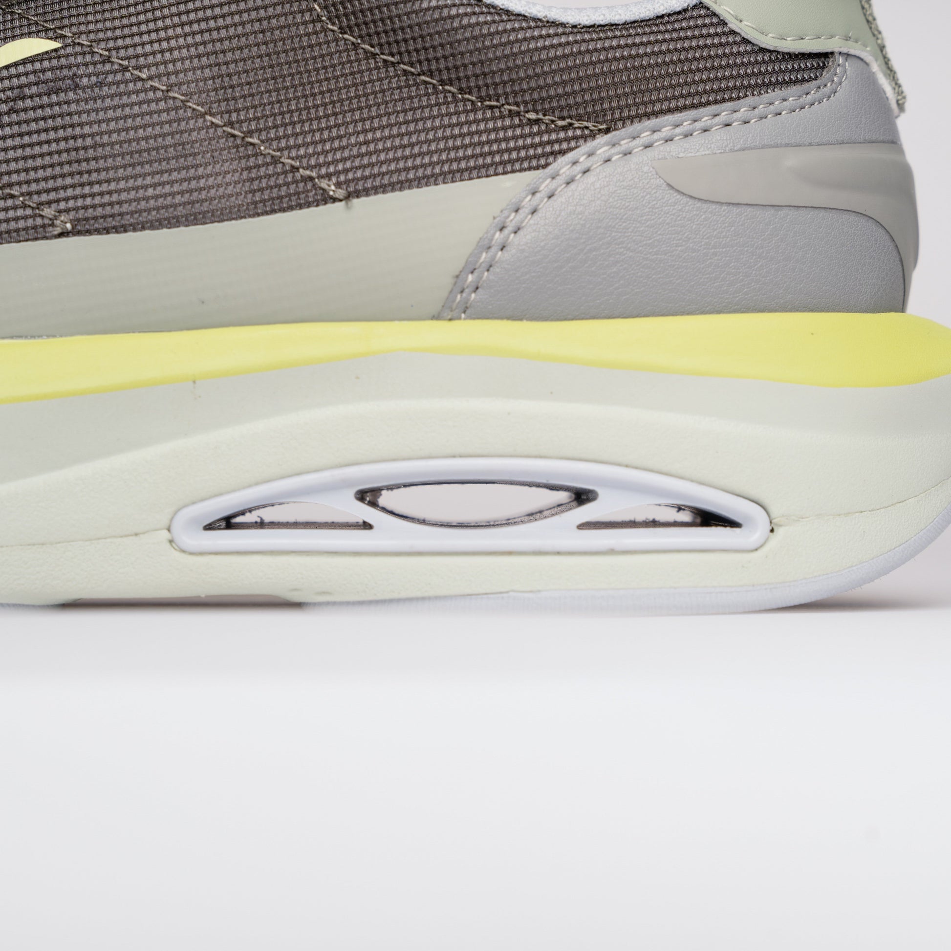 Close-up of a gray and yellow sneaker on a white background